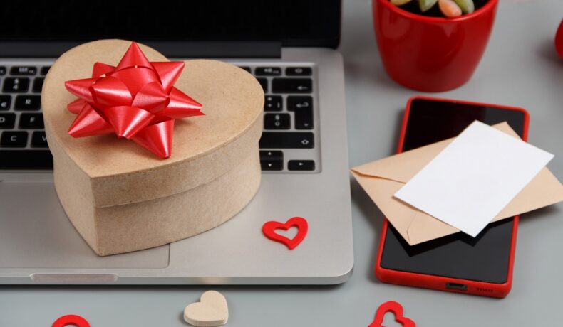 Cadou în formă de inimă, cu fundă roșie, pe un laptop, care se numără printre acele cadouri tech cu prețuri accesibile