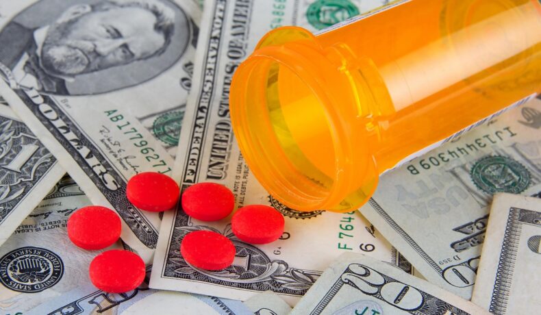 Imagine cu un tub galben de pastile, cu pastile roșii peste dolari, care nu seamănă cu cel mai scump medicament din lume