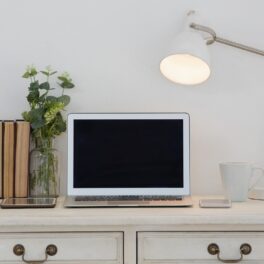 Birou alb cu laptop, lampă, cărți și o plantă, care se numără printre cele mai căutate produse din 2022
