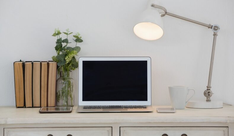 Birou alb cu laptop, lampă, cărți și o plantă, care se numără printre cele mai căutate produse din 2022