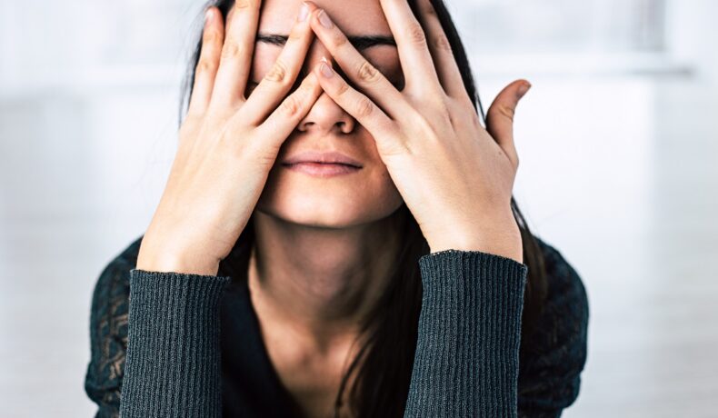 Femeie care pare că plânge, cu mâinile pe față. Misokinesia e fenomenul care poate afecta 1 din 3 persoane
