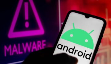 Utilizator care ține în mână un telefon cu logo-ul Android pe ecran, cu semn malware pe fundal. Google avertizează acum milioane de utilizatori Android să șteargă aplicațiile periculoase