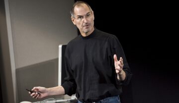 Steve Jobs, îmbrăcat în negru, la un eveniment Apple, pe scenă. Sandalele vechi ale lui Steve Jobs au fost scoase la licitație recent