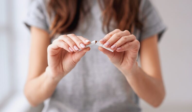 Femeie care rupe o țigară, îmbrăcată în gri. Experții au dezvăluit vârsta ideală pentru a te lăsa de fumat