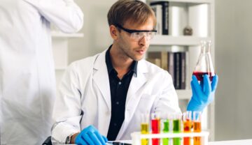 Cercetător bărbat, îmbrăcat în costum alb de laborator, la masă, care studiază o mostră. Potrivit experților, cromozomul Y dispare încet