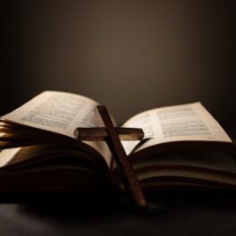 Biblie deschisă, cu o icoană din lemn, pe fundal închis