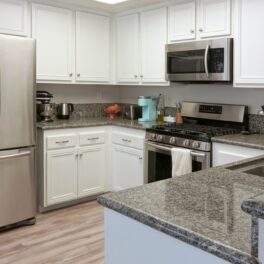 Electrocasnice în bucătărie cu dulapuri albe și blat gri. Printre ele se numără și electrocasnicele care consumă cel mai mult curent