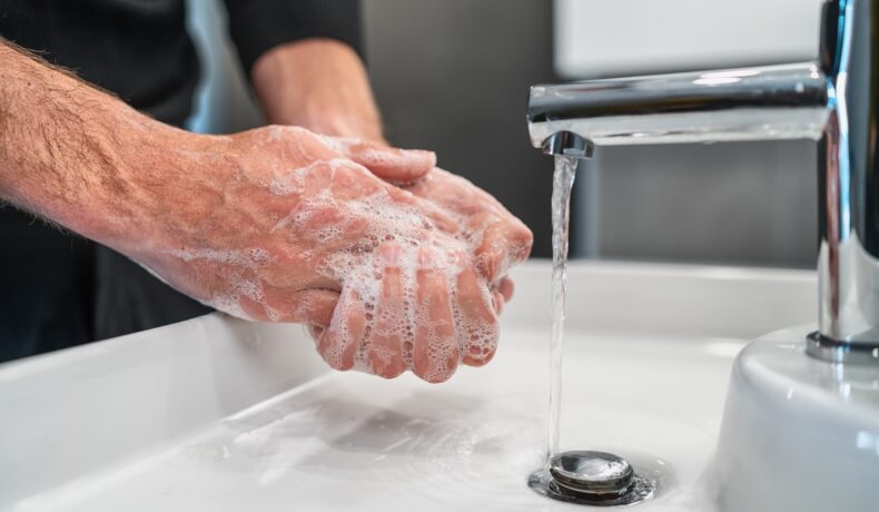 Bărbat care se spală pe mâini, cu o chiuvetă albă. Experții au dezvăluit pericolul care s-ar ascunde în scurgerea de la chiuvetă