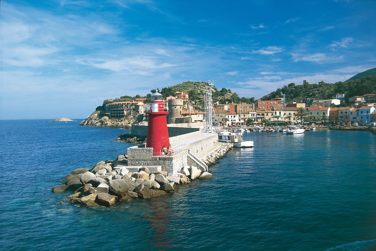 Satul Isola del Giglio, Italia, cu un far roșu în port, înconjurat de apă