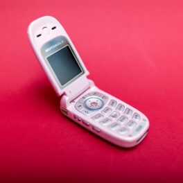 Motorola V220, pe fundal roșu, telefon cu clapetă. Telefoanele mobile cu clapetă revin în tendințe acum