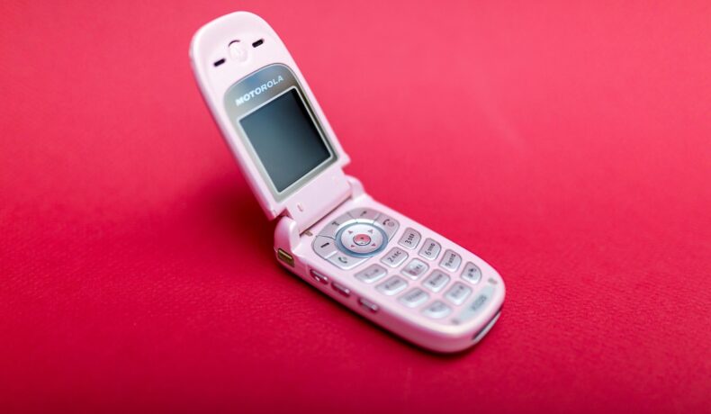 Motorola V220, pe fundal roșu, telefon cu clapetă. Telefoanele mobile cu clapetă revin în tendințe acum