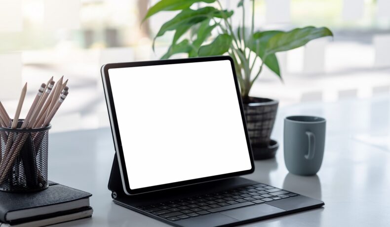 Tabletă cu ecran alb și cu tastatură, pe un birou gri, similară cu OnePlus Pad, care e prima tabletă lansată de companie