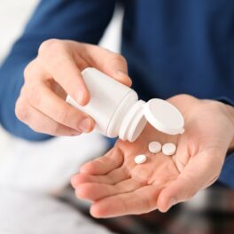 Bărbat care ia medicamente dintr-un borcan alb, similare cu pilula contraceptivă pentru bărbați