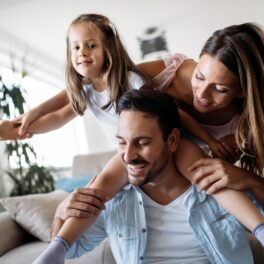Familie cu un bărbat, o femeie și un copil care se joacă, pe canapea, pentru a ilustra cele mai fericite țări din lume în 2023
