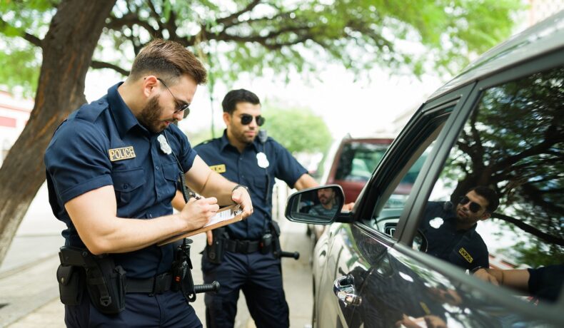 Doi polițiști care scriu o amendă, lângă o mașină neagră, la fel ca în unele dintre cele mai neobișnuite reguli de circulație din lume