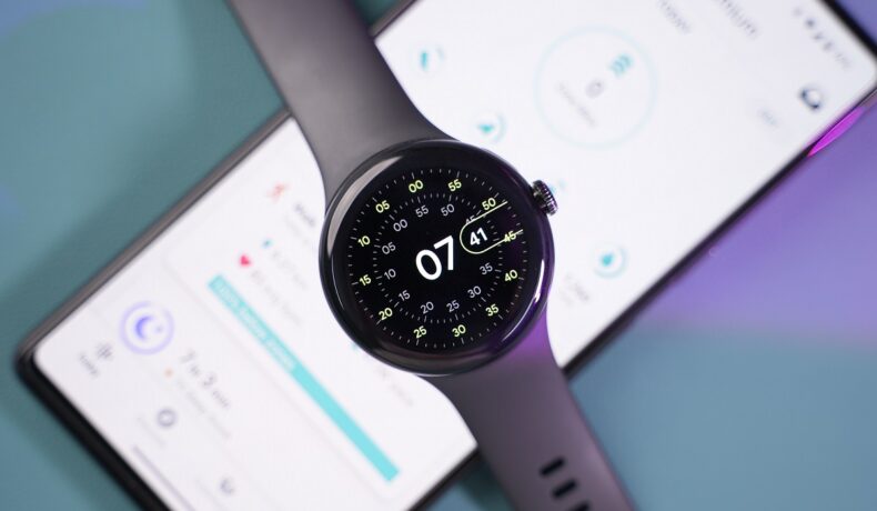 Pixel Watch negru, deasupra unui telefon aprins, pe fundal gri cu mov. Recent, a fost dezvăluit costul de producție pentru Pixel Watch
