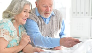 Oameni în vârstă, femeie și bărbat, care se uită la un laptop alb. Experții au dezvăluit recent de ce miros diferit bătrânii