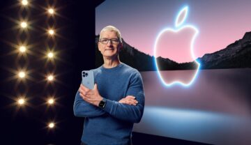 Tim Cook, CEO-ul Apple, cu logo-ul companiei pe fundal și un iPhone ăn mână. Casca virtuală e dispozitivul Apple pe care Tim Cook insistă să îl lanseze