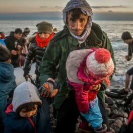Bărbat imigrant care ține de mână 2 copii în timp ce se dă jos de pe o barcă, la fel ca un pescar care risca o sentință de mii de ani