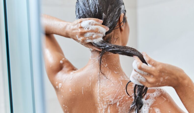 Femeie care se spală pe cap, în baie, pentru a ilustra cât de des trebuie să te speli pe cap