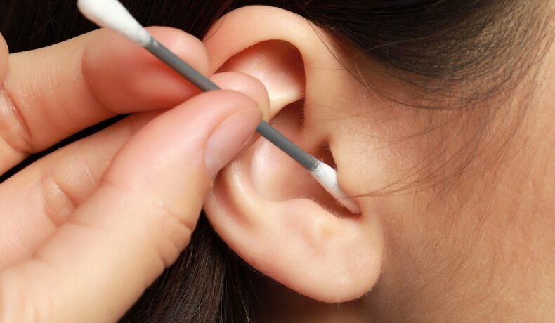 Femeia care se curăță în urechi, pentru a ilustra de ce nu trebuie să folosești bețișoare de urechi