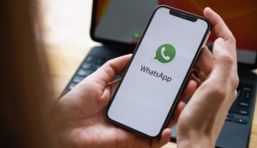 Utilizatoare care ține în mână un telefon cu whatsapp pe ecran, pentru a ilustra cum poți ascunde conversațiile WhatsApp