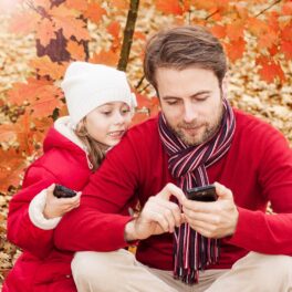 &n tată și o fetiță, amândoi îmbrăcați în roșu, pe fundal de toamnă, pentru a ilustra de ce nu trebuie să folosești telefonul mobil în fața copiilor