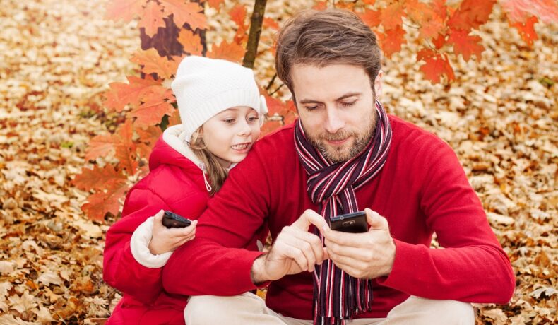 &n tată și o fetiță, amândoi îmbrăcați în roșu, pe fundal de toamnă, pentru a ilustra de ce nu trebuie să folosești telefonul mobil în fața copiilor