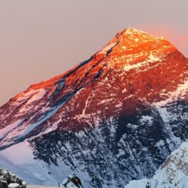 Vârful Everest la apus, cu un cățărător cu rucsac în spate, pentru a ilustra de unde provin zgomotele îngrozitoare de pe munte
