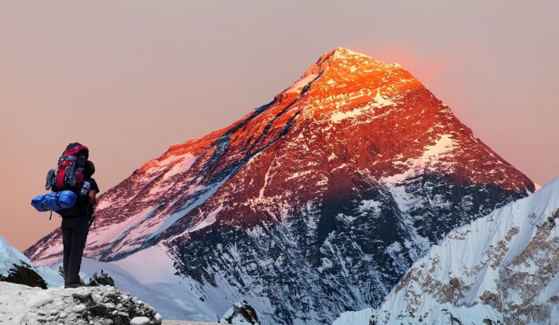 Vârful Everest la apus, cu un cățărător cu rucsac în spate, pentru a ilustra de unde provin zgomotele îngrozitoare de pe munte