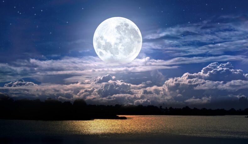 Luna luminoasă pe cer, printre nori, peste o plajă, pentru a ilustra ce se ascunde în centrul Lunii, de fapt