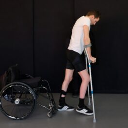 Gert-Jan Oskam, un bărbat paralizat care a putut merge din nou, pe fundal negru, în 2018, cu cârje în mâini și un tricou alb