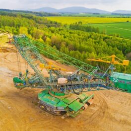 Echipament de săpare minieră de suprafață, verde cu galben, care se află pe vârful unui deal, pentru a ilustra cum China sapă o gaură adâncă de 10.000 de metri