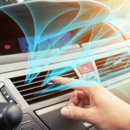 Mâna unui utilizator care folosește aerul condiționat din mașină, cu unde albastre, pentru a ilustra mirosul neplăcut al aerului