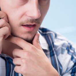 Bărbat cu barbă micuță, îmbrăcat în cămașă în dungi, care vorbește la telefon, pentru a ilustra apelul de 5 minute care ar putea schimba lumea