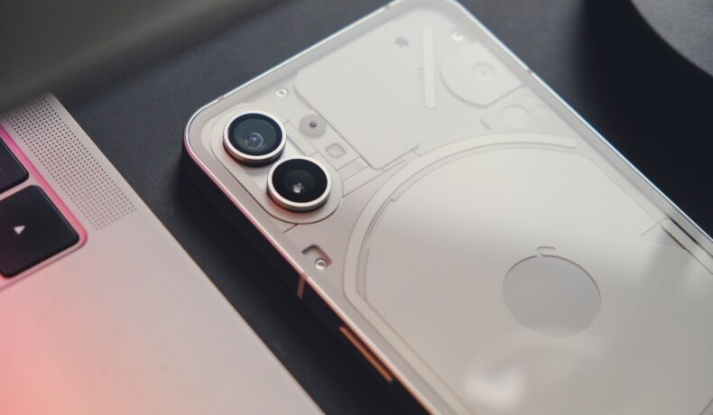 Nothing Phone 1, de culoare albă, pe fundal gri închis, folosit pentru a ilustra cât de rezistent e Nothing Phone 2