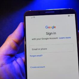Un utilizator care ține un telefon în mână cu Google pe ecran, pentru a ilustra ce știe Google despre tine, cu lumină albastră pe fundal