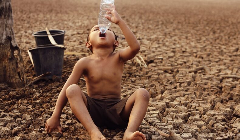 Copil care încearcă să bea dintr-o sticlă de plastic goală, pe un pământ răvășit de secetă, pentru a ilustra cu ce pericol se va confrunta omenirea