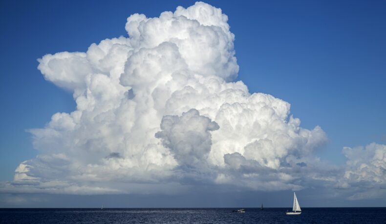 Nor mare alb pe cer, deasupra mării, pe care se află un vas cu velă alb, pentru a ilustra de ce plutesc norii
