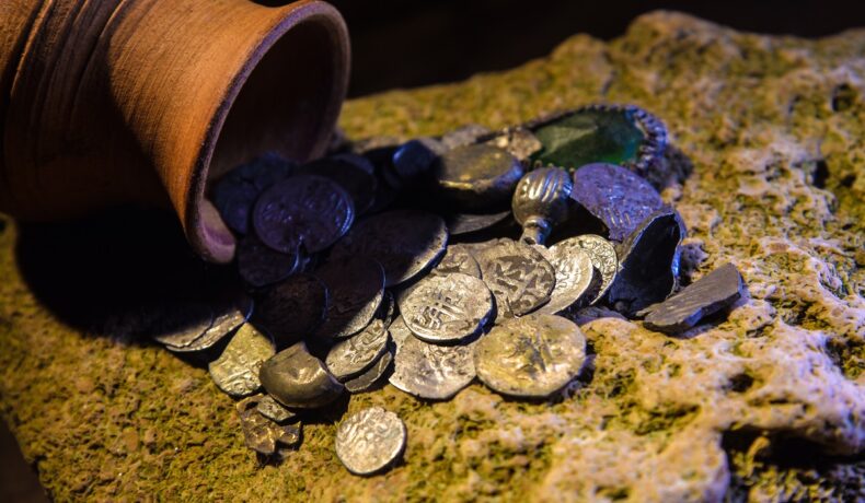 Oală de lut din acre curg monede de argint, pe o piatră, la fel ca o descoperire inedită în România