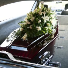 Sicriu maro, cu flori albe deasupra, în mașină funerară, pentru a ilustra prima înmormântare spațială permanentă