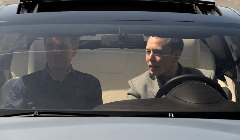Elon Musk la volanul unei mașini Tesla, 2009, alături de designer-ul Franz von Holzhausen. Recent, Elon Musk a încălcat legea când se afla la volan