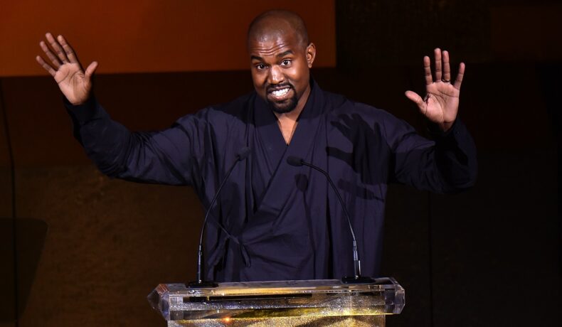 Kanye West, care a revenit recent pe Twitter, pe scenă la CFDA Fashion Awards, 2015, îmbrăcat în negru, cu mâinile ridicate