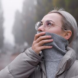 Femeie blondă îmbrăcată în gri care își acoperă gura, pentru a ilustra cât de periculoasă e încălzirea globală