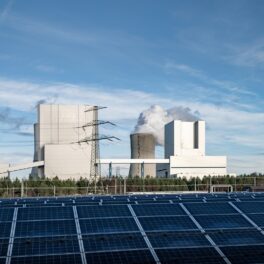 Panouri solare, pe fundal o centrală energetică, pentru a ilustra cea mai importantă sursă energetică