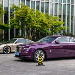 O mașina Rolls Royce mov, e stradă, lângă un Porsche auriu