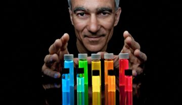 Moungi Bawendi, cercetător MIT, care alături de Louis Brus și Alexei Ekimov a câștigat Premiul Nobel pentru chimie în 2023, pe fundal negru, cu eprubete colorate în fața lui