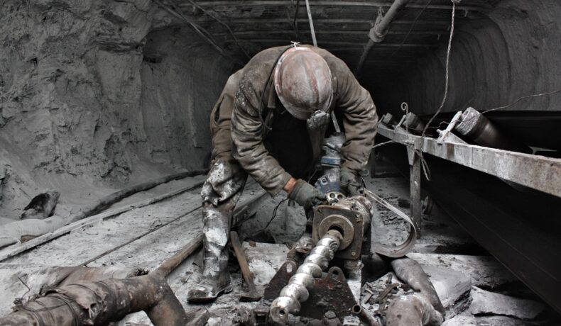 Miner murdar, în intrarea unei mine, similar cu modul în care un investitor a cumpărat o mină cu elemente rare