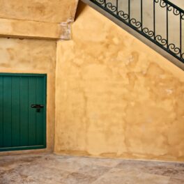 Scări galbene cu o ușă verde dedesubt, pentru a ilustra cum o femeie a vrut să își renoveze apartamentul