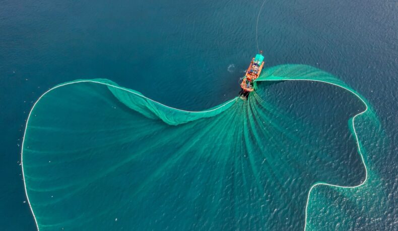 Navă de pescuit, din ocean, cu o plasă imensă, una dintre activitățile clandestine din oceane